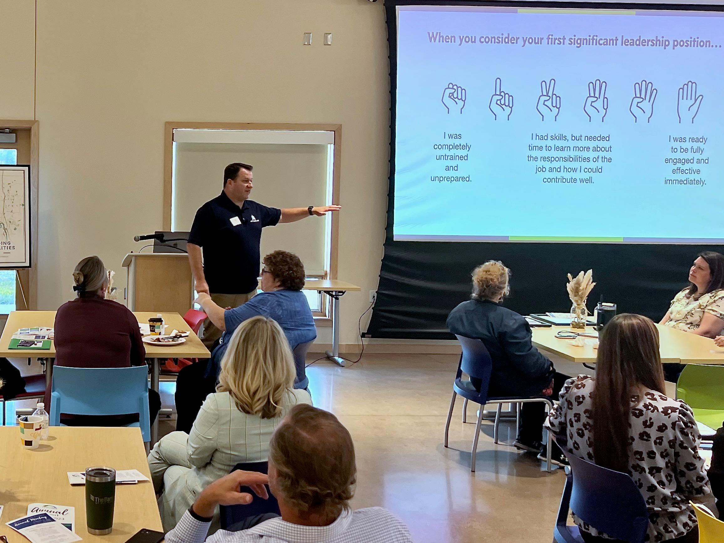 Acuity Leadership Group President Tim Wilson leading a workshop in a brightly lit room with participants arranged at small tables.